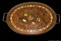 Full view of oval wooden tray with floral inlay and metal handles.