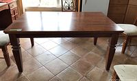 Full view of the rectangular wood dining table showing the top surface and legs on tile floor.