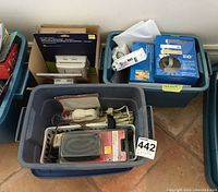 View showing two blue plastic totes filled with electronic items including cords and packaged thermostats