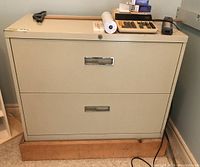 Front view of the metal filing cabinet on wooden base with two drawers and metal handles.