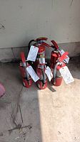 Five red Sentry fire extinguishers grouped together with inspection tags attached, showing condition and quantity.