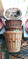 Photo showing large ceramic planter with soil and dried plant debris on surface, sitting on wooden slat, with three woven wicker baskets stacked beside it.