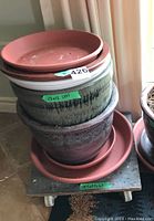 Stacked planters and under trays on wheeled dolly, showing size labels and detailed glazes.
