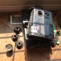 Three Classic portable electric heaters with black plastic housing and rotary control dials, stacked with silver plate and cast iron decorative items on floor tile.