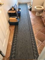 Full view of the dark gray Egyptian runner laid out in a narrow hallway with tiled floor, displaying overall length and placement.