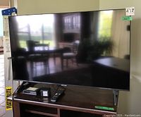 Front view of TV on table with receiver, power adapter and remote visible