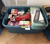 Plastic tote filled with assorted boxed light bulbs and a boxed Fellowes 6 Outlet Surge Protector power bar on top.