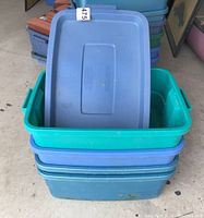 Stack of four Rubbermaid Tough Totes showing lids stacked on top and the teal and blue plastic bodies beneath, with some dirt visible.
