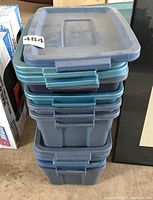 Stack of 7 plastic storage totes with lids in blue and teal colors, showing side latches and flat lids.