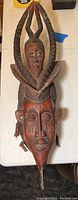 Full view of carved wooden African mask showing face and top horns