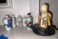 Overview of elder figurine and four porcelain decanters on shelf