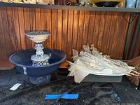 Ceramic bird bath with upper blue and white patterned basin on large blue bowl, faux decorative flowers beside