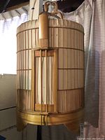 Front view of the bamboo bird house showing vertical bamboo structure and paper sides with no bottom.