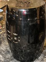 Side view showing barrel shape and cut-out geometric designs on ceramic surface in glossy black finish.