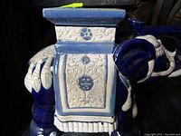 Side view showing the detailed embossed floral and geometric patterns on the side panel of the ceramic elephant stool in blue and white.