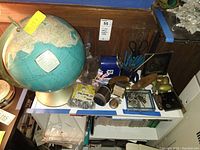 Overview photo showing vintage world globe, blue USPS pencil sharpener, scissors, pens, miniature USPS mailbox with tools inside, pocket watch, assorted hardware and desk organizer tray with small metal items.