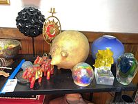 Wide view showing ceramic elephants, pig, various glass decorations, candle holder, and decorative objects on shelf