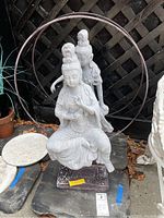 Front view of Asian themed seated statue with hand gesture, white finish, placed on stone base.