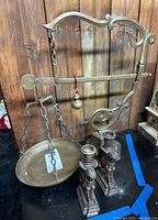 Full view of brass hanging scale with round pan and balancing weight, showing ornate metalwork and chains on pan.
