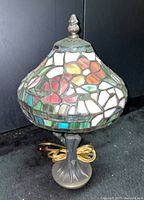 Full view of Tiffany style table lamp showing multicolored stained glass mosaic shade and metal base with owl detail.