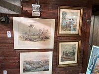 Overall view of four pieces of wall art on a wooden wall; includes two in gold frames and two without frames showing various historical and landscape prints