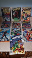 Lot of 9 Daredevil comic books laid out on table, shows front covers with characters and titles.