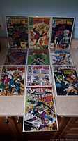 Ten Spectacular Spider-Man comic books arranged on table showing front covers and comic art.