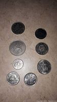 Top view of eight assorted coins showing various designs and denominations from Brazil, Venezuela, France, and Canada.