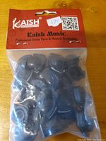 Two sealed packages containing black guitar volume knobs branded Kaish, one with red header card and one with black header card, displayed on a wooden surface.