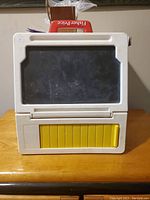 Front view of vintage Fisher Price kids desk showing black screen and yellow slider.