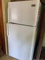 Full view of the white Frigidaire refrigerator, showing the top freezer and bottom fridge compartments with handles.