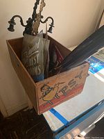 Photo of the wooden Tipp's Pears crate filled with various vintage metal and glass signs and a metal lamp.