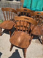 Photo of four wooden spindle back chairs with curved top rails and cutout handles in medium brown wood finish