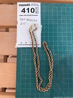 Entire necklace coiled next to measurement note indicating 21.5 inches