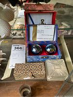 Overview of two iridescent Baoding balls in fabric-lined box, two small decorative boxes, and a clear embossed glass inkwell