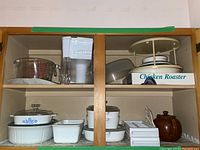 Shelf with glass casserole dish, Brita water filter pitcher, chicken roaster, and stacked casserole dishes
