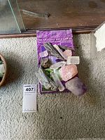 Crystals of varying colors and sizes displayed on The Crystal Ally Cards packaging on carpeted floor.