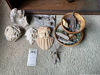 Lot of crystals, stones, and face figures displayed on carpet next to mirror showcasing various carved faces, natural stones and wooden bowls filled with polished stones and crystals