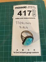 Ring placed on MaxSold lot card showing lot number and handwritten note indicating sterling ring.