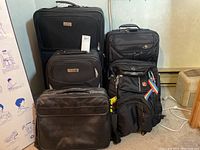 Four black luggage items grouped together showing condition and size relative to each other.