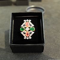 Front view of Art Deco style silver ring with green, pink, and clear stones displayed in black box.