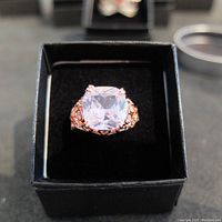 Front view of the ring showing a large clear cushion-cut center stone in decorative silver setting with accent stones.
