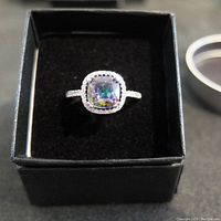 Top view of the estate mystic topaz and diamond type fashion ring in black jewelry box showing center stone and halo setting.