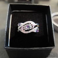 Front view of the ring showing central mystic topaz and decorative silver design with diamond-type stones on band.