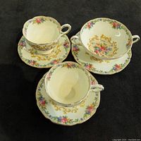 Lot of three Paragon fine bone china items: two teacups with matching saucers and one soup bowl with saucer, floral and gold details on white background.