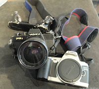 Front view showing Yashica FR1 with large lens and Canon EOS 500 camera body side by side with attached straps.