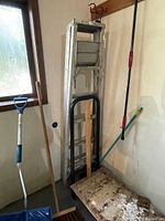 Wide shot showing the aluminum step ladder, dolly, snow shovel and broom leaning against walls.