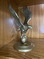 Front angle view of the brass eagle statue on its circular base showing full wing span and detailed feathering.