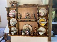 Wide view of wooden shelf displaying various teacups, plates, and figurines.