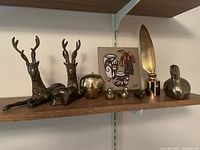 Shelf display showing all brass items and framed artwork.